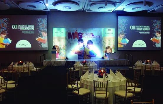 Sala montada con escenario, pantallas y mesas